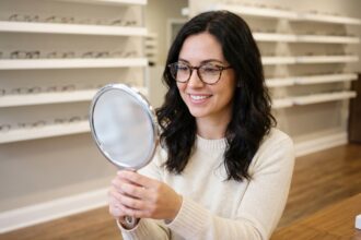 Jeune femme essayant une monture de lunettes écaille dans une boutique d'optique moderne